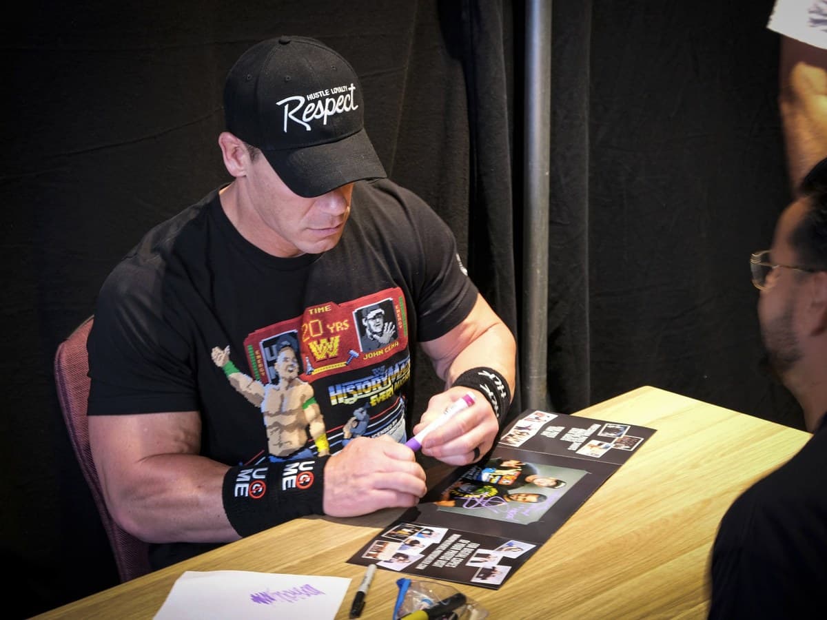 Celebrity signing an autograph for a fan at a Comic-Con meet-and-greet